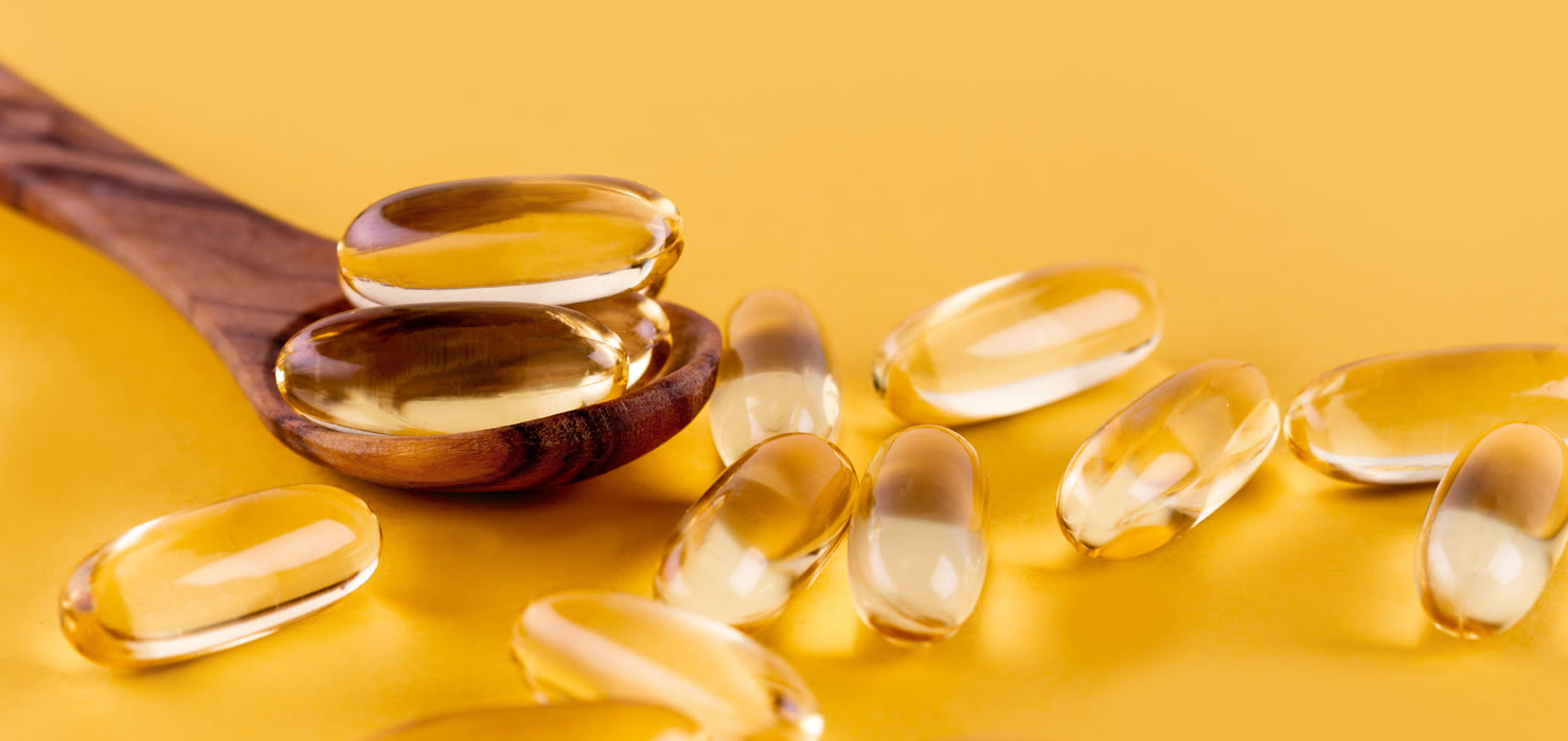 Omega-3 fish oil capsules on a yellow surface
